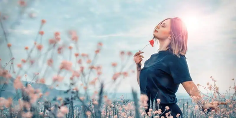 woman in field of flowers holding one under her chin - BTL Emsella Chair