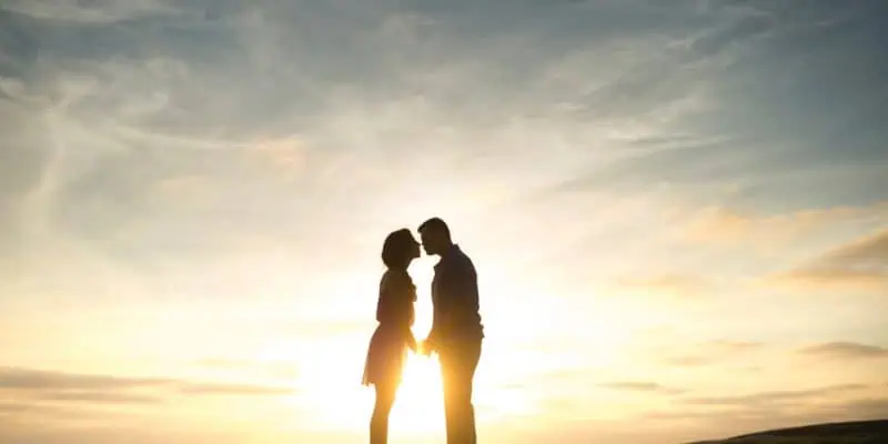 silhouette of couple facing each other with sun rising behind them