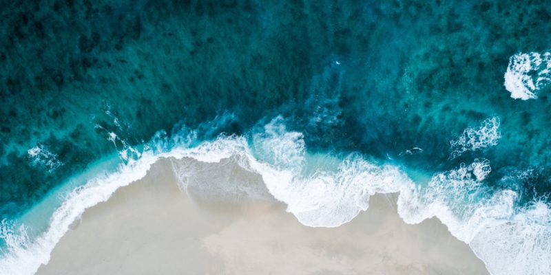 aerial view of ocean crashing against the shore